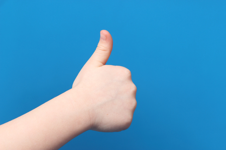 gesture thumb up isolated on blue backgroundの写真素材