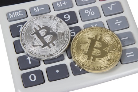 gold and silver bitcoin lies on a white calculator. electronic money and cryptocurrencyの写真素材