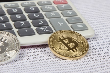 gold and silver bitcoin lies on a white calculator. electronic money and cryptocurrencyの写真素材