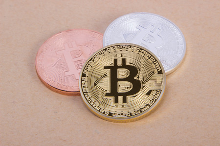 gold silver and bronze coins bitcoin on the background of bright paper