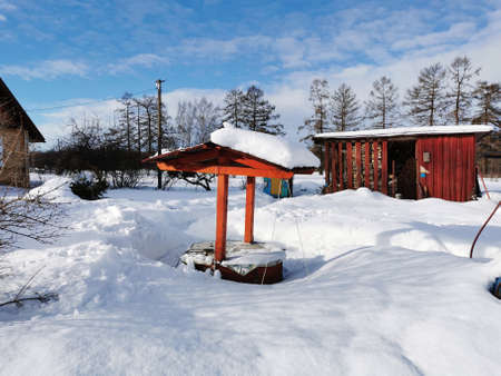 winter day in the Russian village snow well blue skyの写真素材