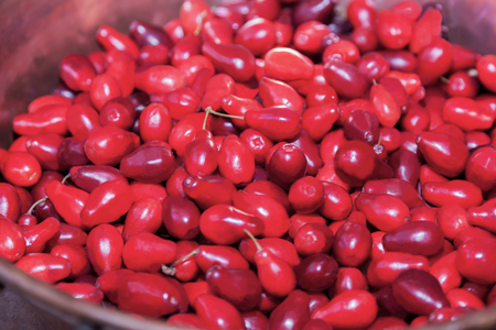 Bright red dogwood (cornel) in vintage copper bowl on the ceramic floor. Close up, indoors.の写真素材