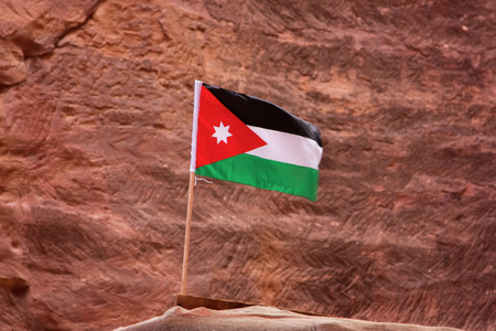 The flag of Jordan, shooting in the ancient stone city Petra, on the red rock background, close-up, outdoors. Copy space.の写真素材