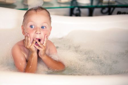Surprised cute kid holding hands in surprised gesture, keeping mouth wide open, looking shocked in...