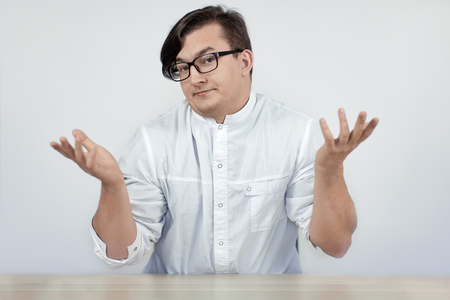 Young handsome man wearing doctor or scientis white coat with disbelief gesture (hands up) and excited perplexity face expression. Indoors, copy space.の写真素材