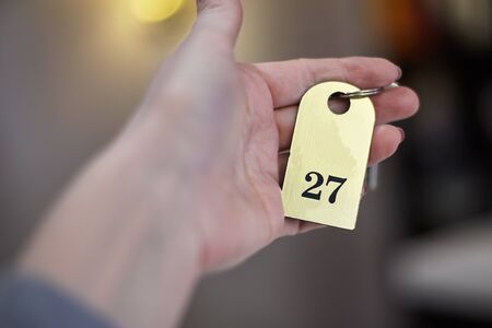 The woman hand holding the hotel room key. Selective focus, indoors, copy space.