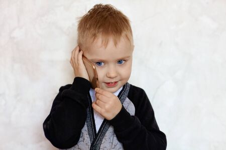 Cute little blond boy with blue eyes talks on mobile phone, smiling. Children and modern technology...