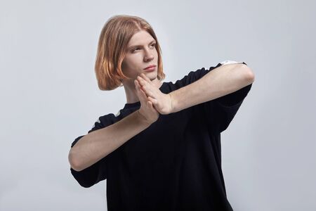 Young handsome effeminate caucasian man with ginger hair and green eyes poses in studio, making...