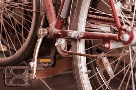 Two old dusty bicycles standing in closet under the stairs. Close up wheel, spokes, transmission chain and pedals. Copy space. の写真素材