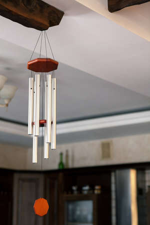 Traditional Chinese Feng shui interior object called chime tree or wind music, made from steel tubes. Relaxation, cleansing aura and defense from negative energy, hanging on the wooden bar on ceiling.の写真素材