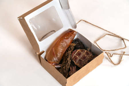 Some cut pieces of dehydrated beef treats for pets in a little cardboard box, dry dog food, home-made and natural. White background, close up, copy space.の写真素材