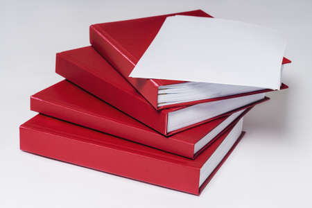 Stack of red hardcover books or reports with empty sheet of paper on the top, on white background. Copy space.の写真素材