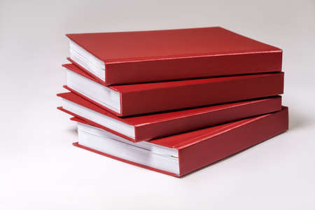 Stack of red hardcover books or reports on white background. Copy space.の写真素材