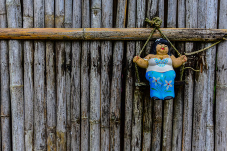 Woman Clay Sculpture Hanging In Front Of Old Bamboo Door.の写真素材