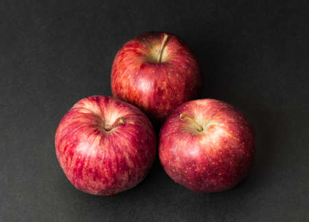 Three whole fresh apple fruit isolated on black texture background