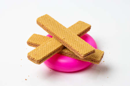 Delicious vanilla wafer stacks on a pink plastic  tube isolated on white background