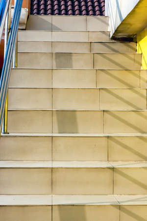 Close view of stairs with yellowish tiles and railing