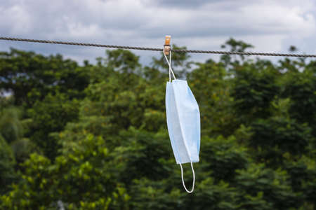 A wet surgical mask hanging with a clothesline to dry in the sunの写真素材