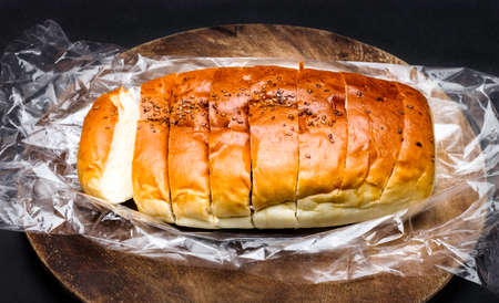 Sliced whole wheat bread above a wooden round chopping board on dark backgroundの写真素材