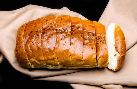 Sliced soft wheat bread close up view above a brown cloth on isolated dark backgroundの写真素材