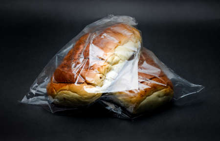 Close up view of two delicious wheat bread inside of transparent polybag on dark texture backgroundの写真素材