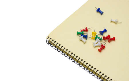 Different colored paper push pins on notepad with white copy spaceの写真素材