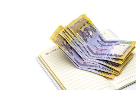 Few one thousand taka bangladeshi banknotes above a notebook on isolated white background with copy spaceの写真素材