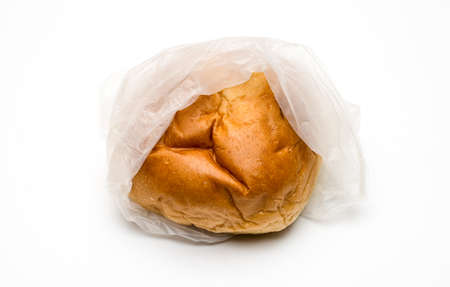 A delicious hamburger bun inside of a transparent polybag on white background