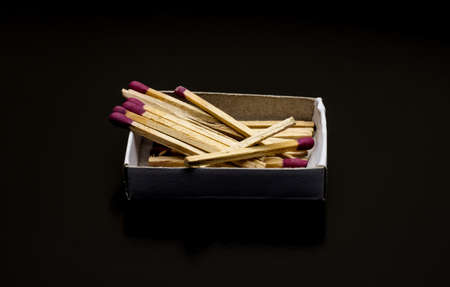 Few scattered matchsticks above a small box on dark backgroundの写真素材