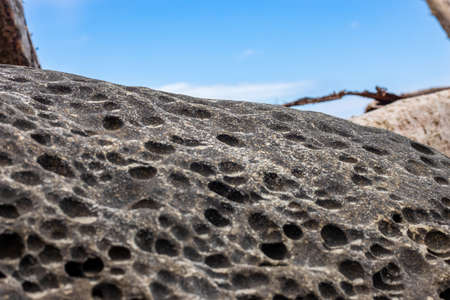 Close up view of a rough stone under the blue sky with selective focus
