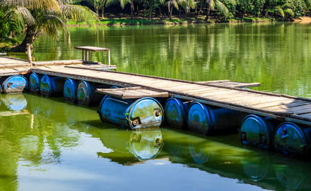 A wooden bridge over the canal made with recycle plastic drumの写真素材