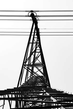 Bottom view of cable hanging arm of electrical transmission tower under the foggy skyの写真素材
