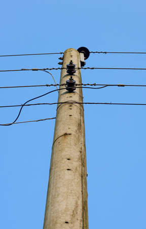 Close up bottom view of aged electricity pole under the blue sky