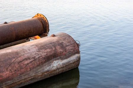 Abandoned dredging pipes on the river close up shot with copy space