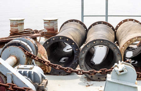 Rustic anchor machine and stored abandoned pipes on a dredging ship close upの写真素材