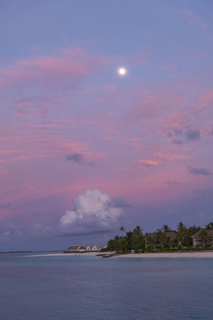 Tropical beach at sunset with a full moon in the skyの写真素材