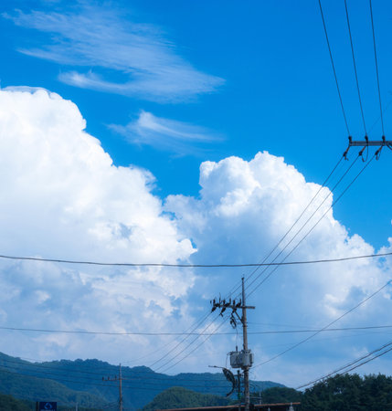 High voltage pole with blue sky and white cloud background.の写真素材