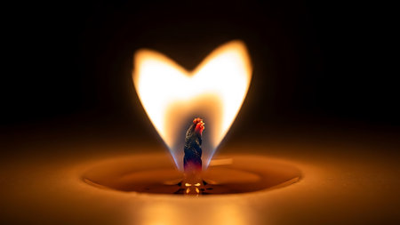 Close up of candle flame forming perfect heart shape, casting warm glow in dark, intimate setting. Melded wax pool enhances the romantic and serene atmosphere, symbolizing love and warmth.の素材