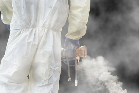 A man hold a gas mask in the smoke. black background