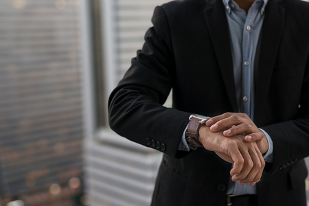 Businessman look his watch, modern building in Business district at Bangkok city background.  engagement business conceptの写真素材