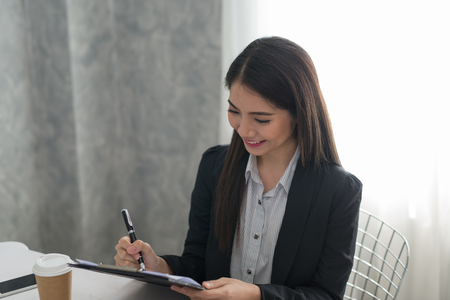 Beautiful asian young businesswoman. Happy working in her workstationの写真素材