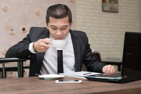 handsome asian businessman drinking coffee in cafeの写真素材