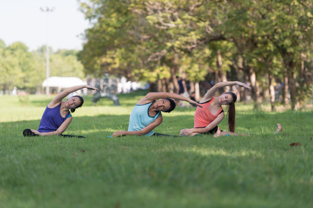Family practicing yoga in the park outdoor. Concept of healthy lifestyle and relaxation.の写真素材
