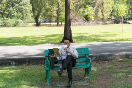 Businessman sit check email on digital tablet at the garden on the way back home.の写真素材