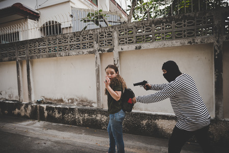 Thieves use a gun to force a woman to submit your property is worth.の写真素材