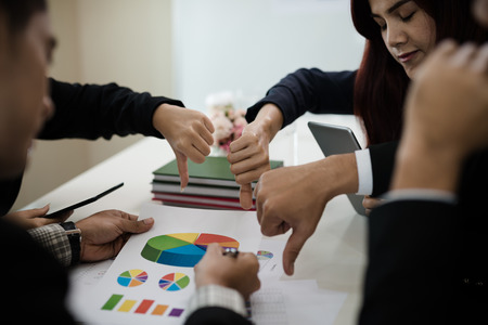 Groups of Asian businessmen show dislike or unlike thumbs down hand. The feedback at the meeting.の写真素材