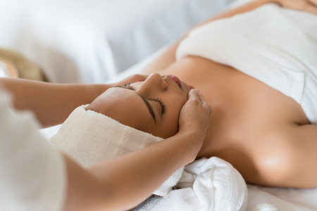 Beautiful Asian girl relaxing receiving facial massage in a spa salonの写真素材