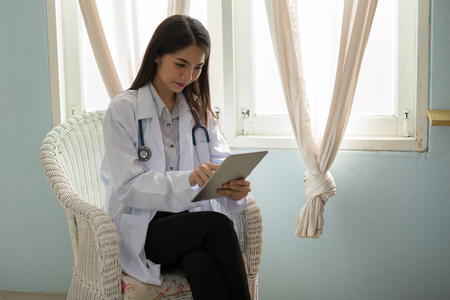 Doctor smiling Asian woman working on a digital tablet.の写真素材