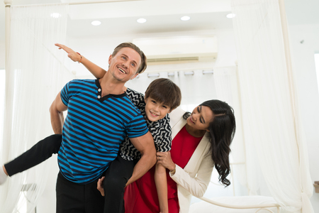Father,Mom and Son are smiling while playing airplane spending time together with having fun in the Houseの写真素材