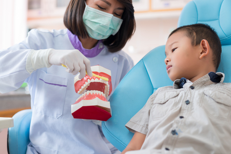 Asian female dentist talking to brush teeth properly explained to the boys were listening to in the hospitalの写真素材